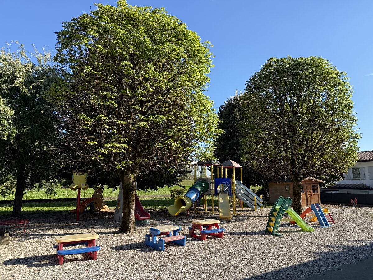 Il parco-giardino esterno con scivoli, casetta di legno, tavolini e alberi