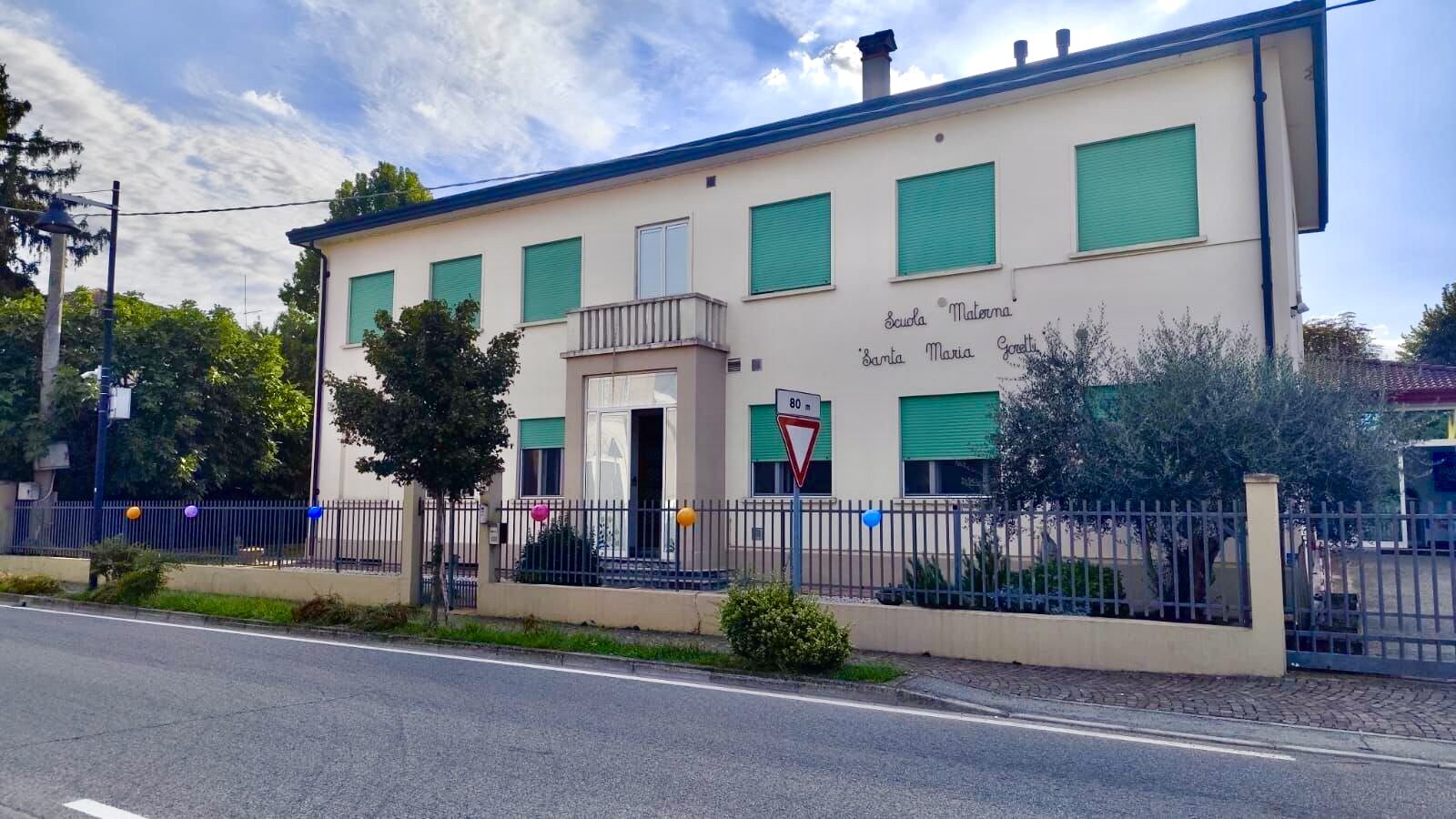 La scuola vista dalla strada, con il nome scritto sulla facciata e il cancello d'ingresso su Via Molini
