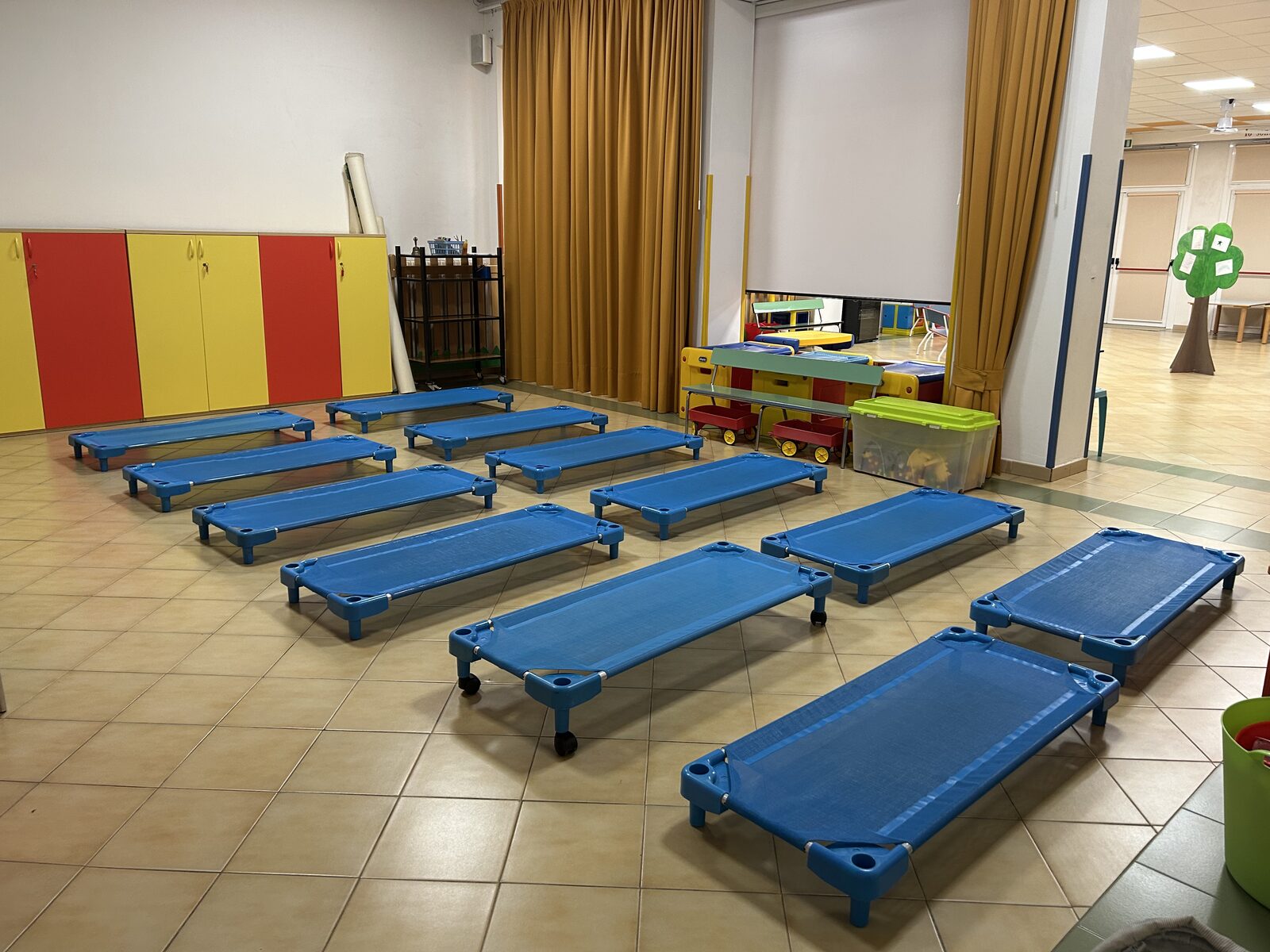 La stanza nanna con i lettini azzurri preparati sul pavimento, gli armadietti gialli e rossi e le tende che separano l'ambiente