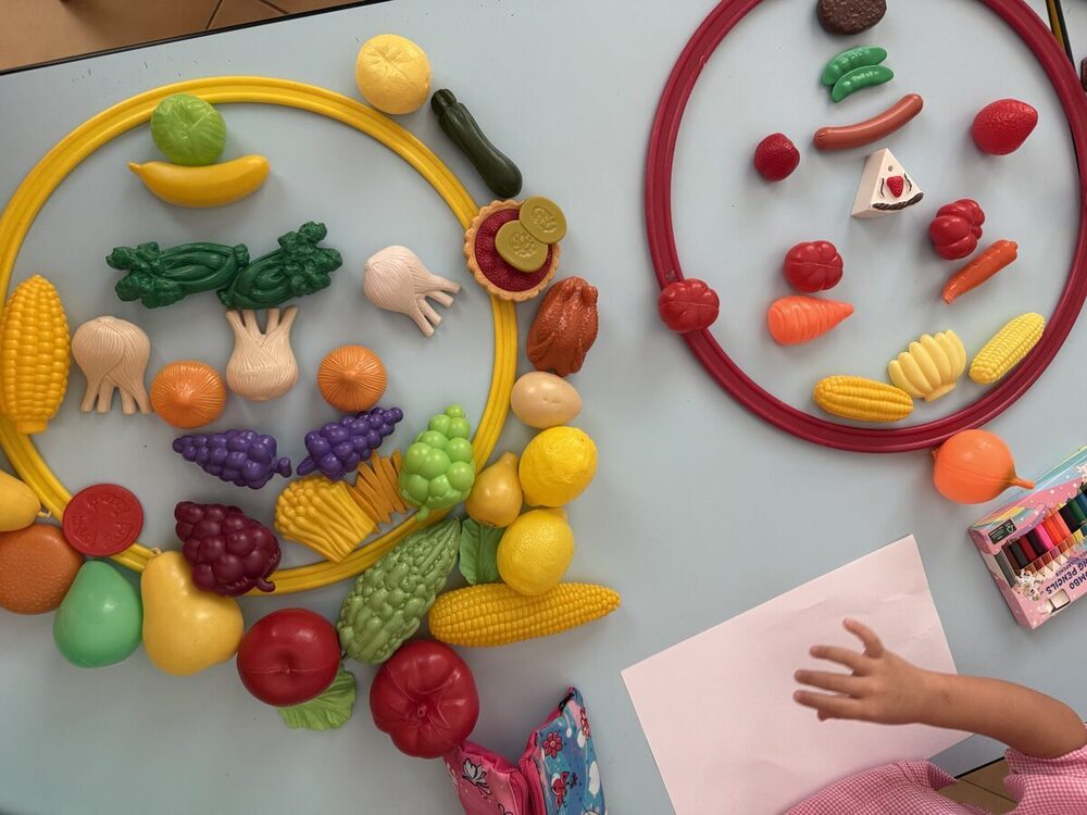 Frutta e verdura giocattolo raggruppate dai bambini dentro due cerchi colorati