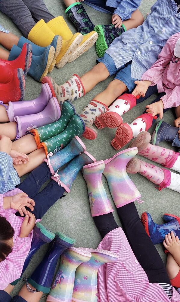 Bambini seduti in cerchio con gli stivaletti di gomma colorati