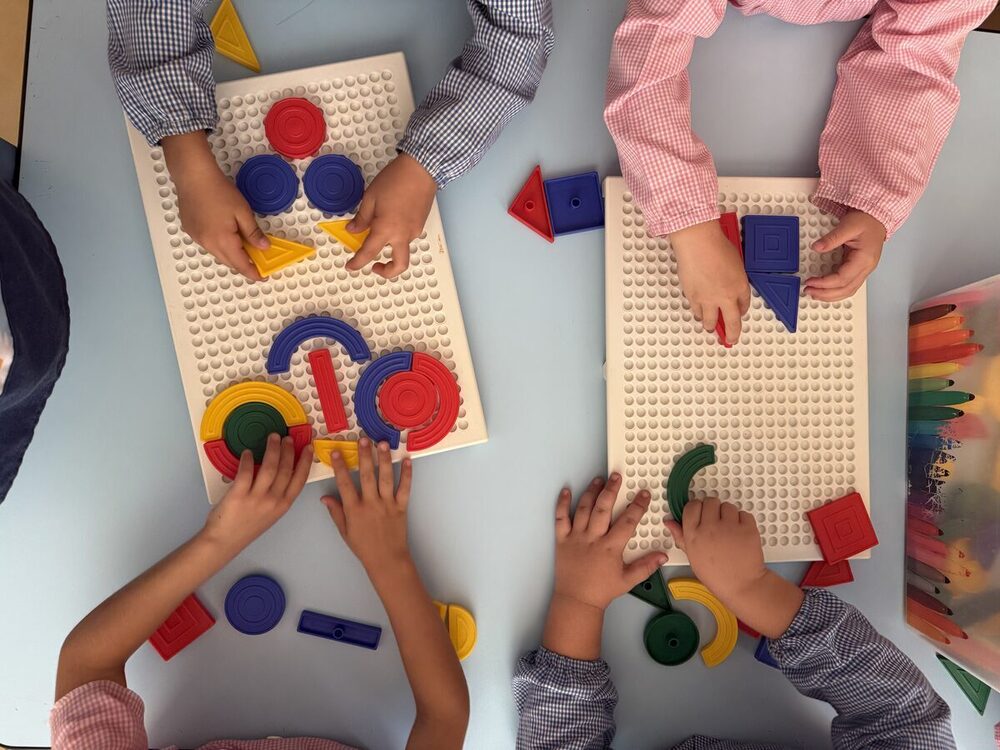 Bambini che compongono figure con incastri geometrici colorati sulle basi forate