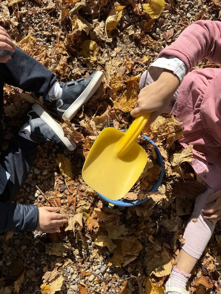 Bambini che raccolgono foglie autunnali con paletta e secchiello