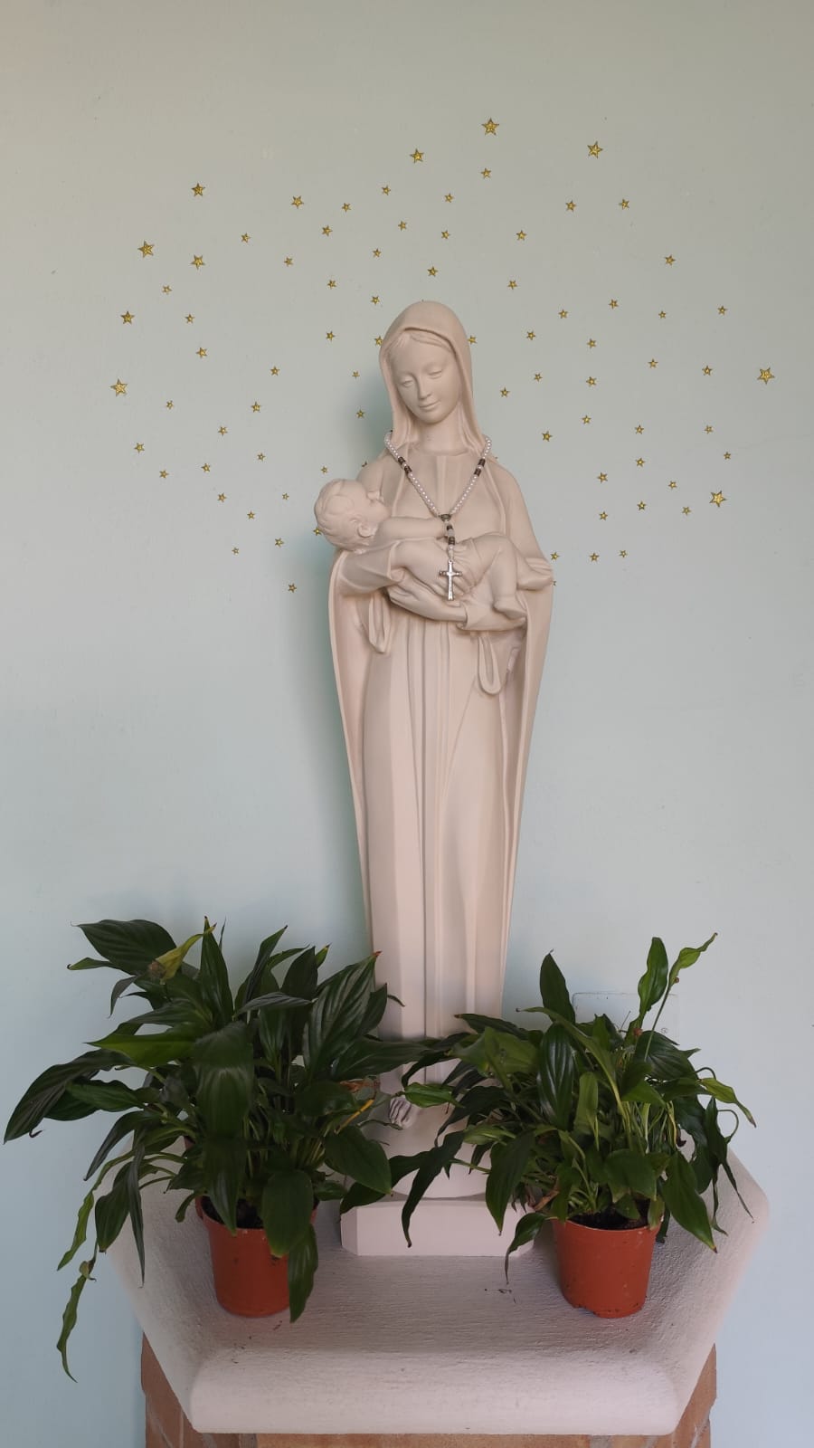 La statua della Madonna con il Bambino nella scuola, su una parete decorata con stelline dorate